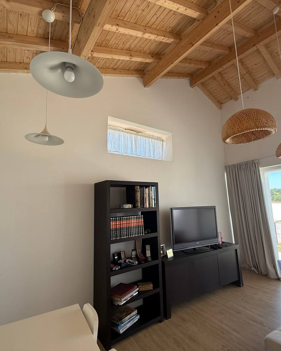 The living room with wooden beams, woven pendant lights and a bookcase